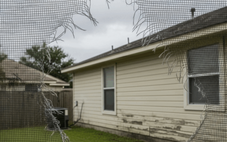 Window screen damaged by UV rays and storms on a suburban Houston home, illustrating climate-related wear and You need window screen repair services